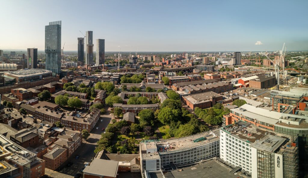 Image shows an aerial shot of buildings with three skyscrapers in the distance